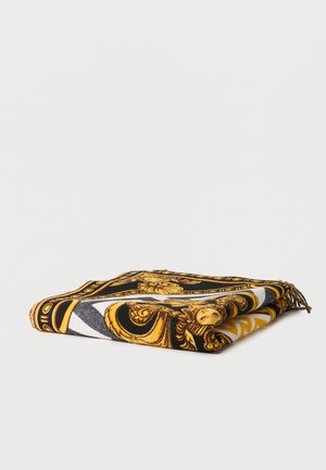 Διπλωμένο κασκόλ με μαύρα, χρυσά και λευκά περίτεχνα μπαρόκ μοτίβα και φούντες σε μία γωνία, εμφανιζόμενο σε λευκό φόντο.