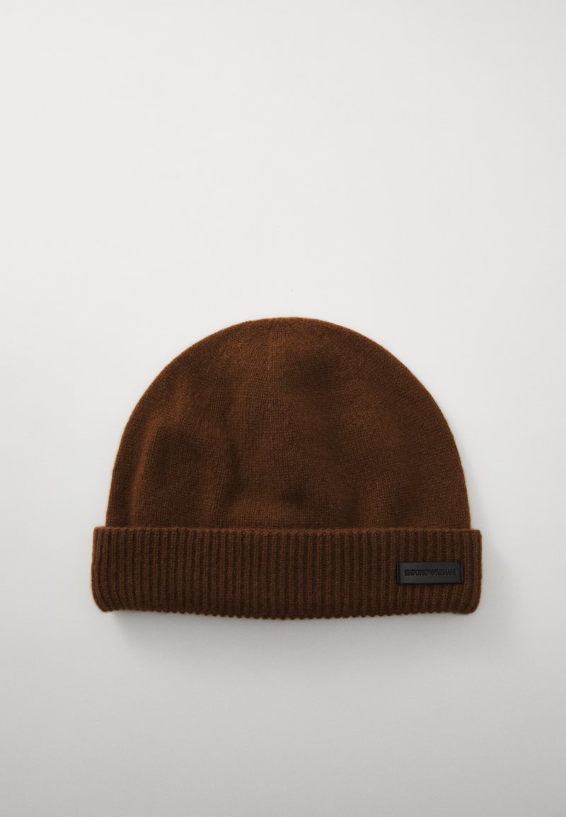 Καφέ μπερέ από πλέγμα με μαλακή υφή, διαθέτει ριγωτό μανίκι και μια μικρή μαύρη ετικέτα λογότυπου. Στρογγυλή κορυφή με αδιάσπαστη σχεδίαση.