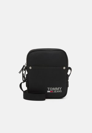 Sort Tommy Jeans crossbody taske med frontlomme, justerbar skulderrem og logo i hvid, rød og blå på ensfarvet baggrund.