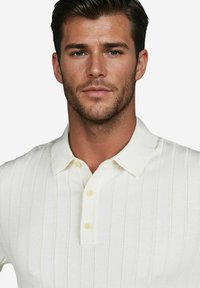 Elfenbeinfarbendes, gestreiftes Polo-Shirt mit Knopfleiste, kurzen Ärmeln und strukturiertem Stoff mit vertikalen Streifen.