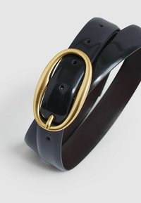 Zwarte gepatineerde leren riem met een gouden ovale gesp, voorzien van meerdere verstelgaten en een gladde textuur.