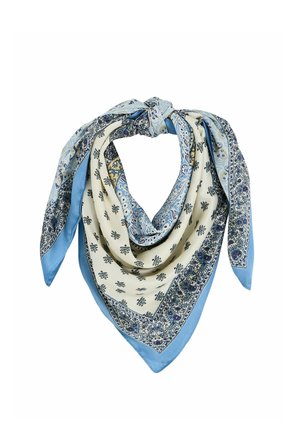 Pañuelo de seda con patrones de cachemira y florales en azul y crema, atado en un nudo suelto, mostrando capas de tela y un diseño detallado en el borde.