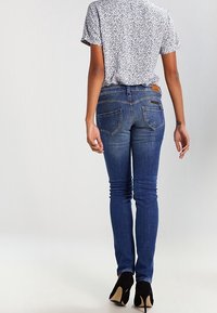 Smala blå jeans i denim med medelhög midja, subtila blekningar och två bakfickor. I kombination med en mönstrad kortärmad topp.