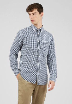 Camicia a quadri blu marina e bianca in cotone, con taschino sul petto, maniche lunghe e colletto classico. Texture liscia e vestibilità su misura.