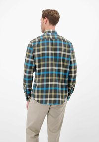 Koszula w kratę z długim rękawem w odcieniach oliwkowej zieleni, granatu i niebieskiego, z kołnierzykiem zapinanym na guziki i zaokrąglonym dołem. Miękka flanelowa tekstura.