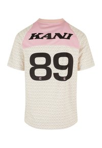 Krátký rukáv, krémové tričko má růžovou horní část, na zádech velké černé "89" a černé logo KANI nahoře, s texturovaným vzorem.