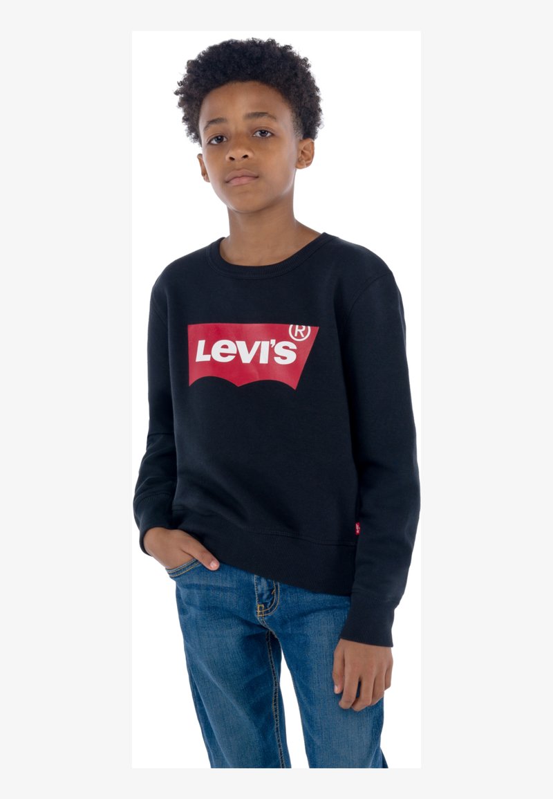 Svart hettegenser laget av bomull med rund hals. Har en stor rød Levi's-logo på fronten. Kombinert med blå denimjeans.