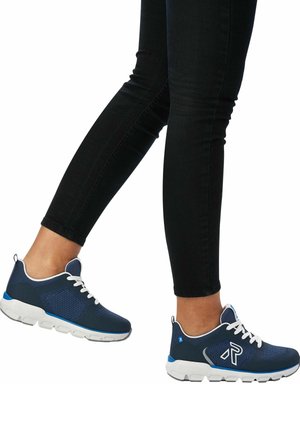 Blue mesh athletic shoes with white laces, featuring a cushioned white sole and blue accents, shown on a person wearing black jeans.
