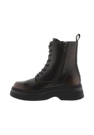 Botas de tobillo de cuero marrón con una suela de goma negra gruesa, que presentan cordones planos, un zipper lateral y una tira en la parte posterior para ayudar a ponérselas.