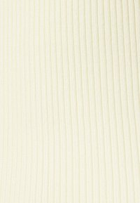 Gros plan sur un tissu en tricot côtelé de couleur crème avec des lignes texturées verticales.