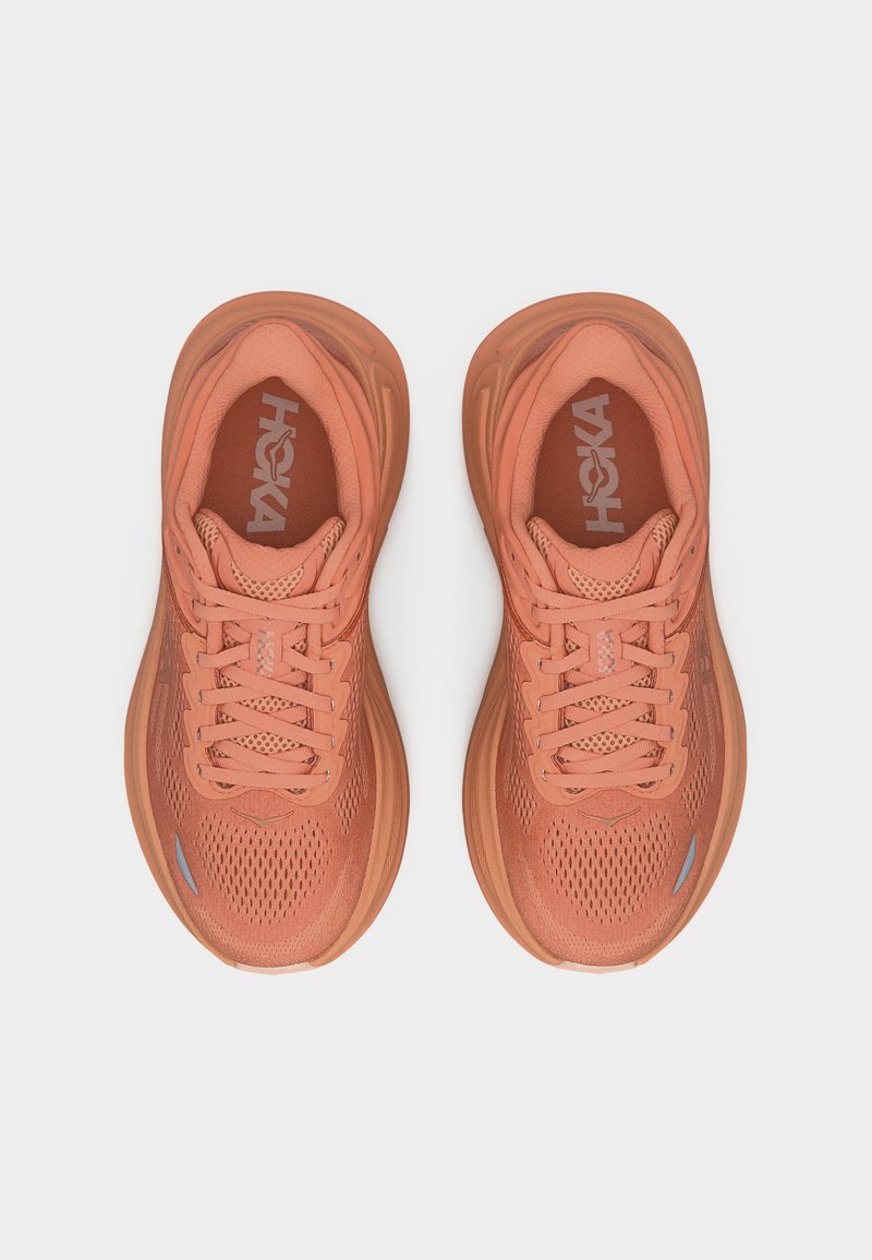 Paire de chaussures de course HOKA couleur orange corail avec tiges en mesh et semelles épaisses et rembourrées, vues de dessus sur fond blanc.
