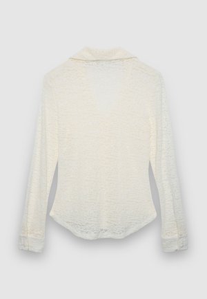 Weißes, strukturiertes Langarmhemd mit Kragen, geknöpften Manschetten und leicht geschwungenem Saum. Ein dezentes Muster sorgt für visuelles Interesse.