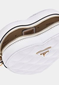 Hvid quiltet rund lædertaske med en guld lynlås og logo-accent. Har dobbelt lynlåslukning og glat foring indvendigt.