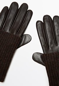 Bruine leren handschoenen met geribbelde gebreide manchetten, voorzien van een gladde afwerking, vijf vingers en stikdetails langs de naden.
