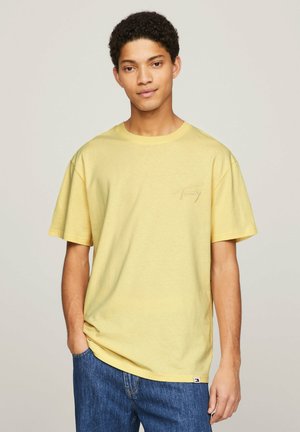Camiseta de algodón amarilla con mangas cortas y cuello redondo, que presenta un pequeño logotipo bordado en el pecho y un corte relajado.