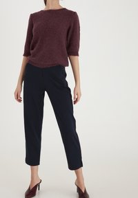 Burgundy kortärmad tröja med strukturerad yta, ihop med marinblå capribyxor och burgundy klackmules.