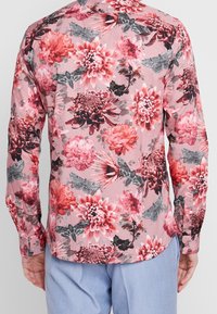 Langärmlig shirt in roze met een bloemmotief, met grote bloemen en nachtvlinders. Gladde stof met een afgeronde zoom en mouwboorden met knopen.