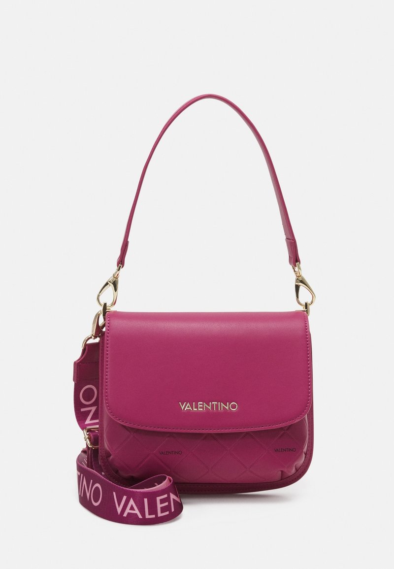 Rosa Valentino axelremsväska med quiltad nederdel, guldfärgad hårdvara och avtagbar bred rem med "Valentino" tryckt i ljusrosa.