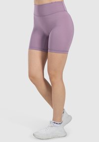 Pantalones cortos deportivos de talle alto en un suave color púrpura, elaborados con material elástico, que presentan costuras suaves y un diseño ajustado.