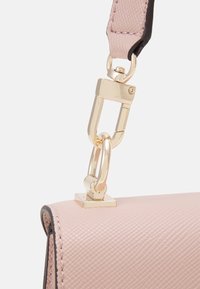 Różowa torebka teksturowana w rogu z złotym zapięciem metalowym i detalami łańcucha, posiadająca kwadratową bazę oraz kontrastowe czarne wykończenie.