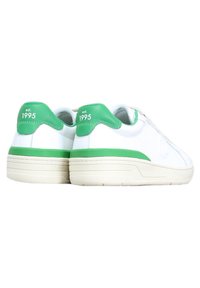 Sneakers bianchi con accenti verdi sul tallone e sui lati, caratterizzati da una tomaia testurizzata e una suola spessa di colore chiaro. "est. 1995" stampato sul tallone.