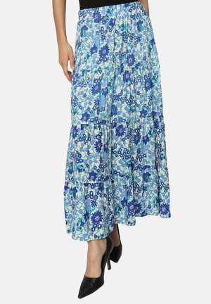 Jupe maxi florale avec un design en étages. Présente des motifs floraux bleus et blancs. Fabriquée en tissu léger, associée à des talons noirs.