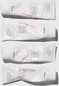 Quatre tubes blancs de Crème de Céramide Comfort de COSRX, présentant une texture lisse, un texte noir et une fine ligne d'accent rose à l'avant.