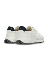 Sneaker blanche avec une tige en cuir lisse, un onglet de talon en suède marine avec deux étoiles dorées, et une semelle en caoutchouc noir avec des rainures de traction.