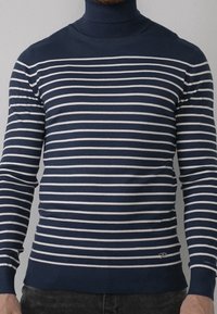 Maglione a collo alto blu navy con righe bianche orizzontali, polsini e orlo a coste, con un piccolo logo sul lato sinistro in basso.