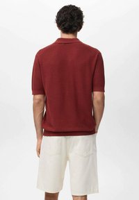 Maroon knit polo shirt with short sleeves, ribbed texture, and collar, paired with white shorts. Rear view shows subtle seam details.