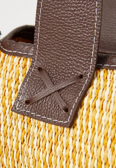 Woven straw bag featuring a yellow and natural color scheme, with a brown leather handle stitched with white detailing.