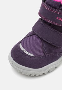 Scarpa per bambini di colore viola con un mix di tessuto testurizzato e suede liscio. Due fasce in velcro e dettagli rosa a contrasto aggiungono un tocco di stile.