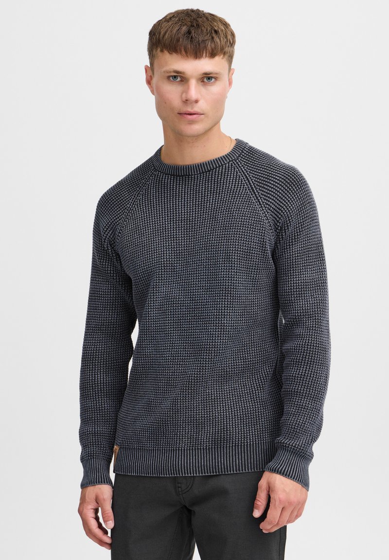 Marineblauer Strickpullover mit strukturiertem Muster, geripptem Rundhalsausschnitt und -bündchen, mit einem kontrastierenden Saum und einem Markenpatch an der Seite.