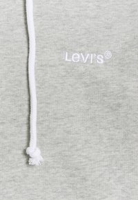 Felpa grigia chiaro in morbido cotone misto, dotata di un cordino bianco e del logo "Levi's" ricamato in filo bianco sul davanti.
