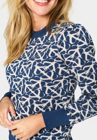 Pull bleu marine avec un motif abstrait blanc, col rond côtelé et poignets, et une texture tricotée douce.