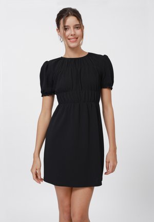 Black short dress featuring puff sleeves, a gathered bodice, and a flowing silhouette. Made from textured fabric with a smooth finish.
