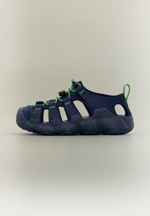 Sandalo open-toe blu navy con lacci verdi, punta rinforzata, suola imbottita e anello sul tallone su sfondo neutro.