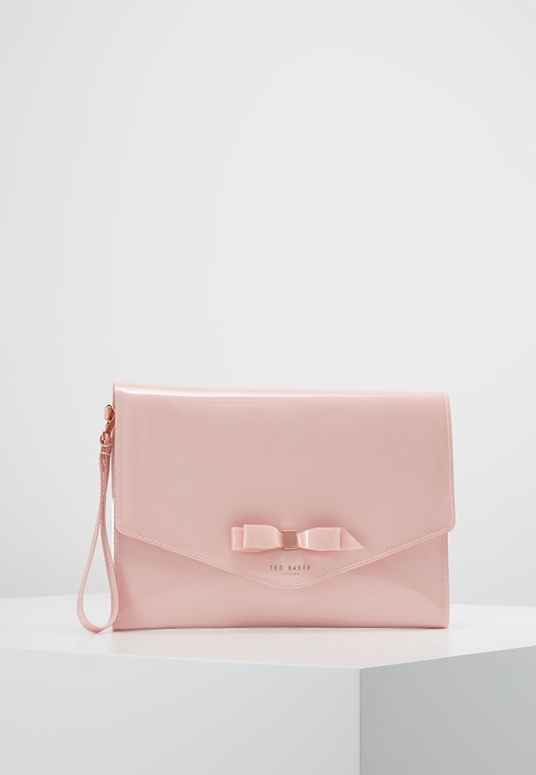 Pochette en cuir verni rose avec rabat à rabat, détail nœud décoratif et une sangle pour poignet. Présente un logo métallique à l'avant.