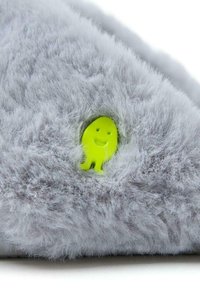 Un matériau en peluche gris avec une texture douce présente une petite icône de fantôme souriant jaune partiellement intégrée.