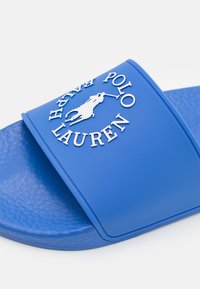 Blå gummisandle med texturerad fotbädd och vit Polo Ralph Lauren-logotyp med en polo ryttare på remmen.