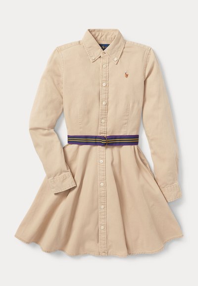 Beigā krāsā kokvilnas krekla kleita ar pogu aizdari priekšā, garām piedurknēm, norādītu apkakli un daudzkrāsainu svītru jostu ap viduku.