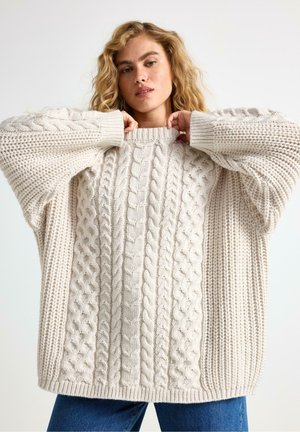 Paksu neulepusero kreemivalkoisena, jossa on köysikuvioita, ribattu hihansuu ja rento istuvuus pyöreällä kaula-aukolla.