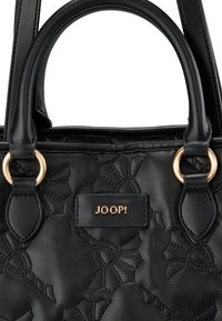 Sac à main en cuir noir texturé avec des motifs floraux en relief, poignées rondes en haut et un accent en métal doré avec le logo de la marque.