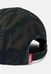 Dark denim baseball cap with a faded, textured finish. Features a back opening and a red "DIESEL" tag on the strap.