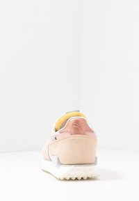 Baskets aux couleurs pastel avec une tige en daim, des détails en mesh et une semelle en caoutchouc texturée. Présentent un logo près du talon et un renfort à l'arrière.