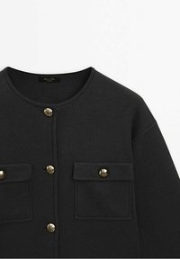 Cardigan noir en maille avec encolure ronde, deux poches avant, orné de quatre boutons dorés sur le devant et sur les poches.