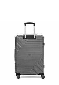 Valise rigide grise avec des rainures horizontales et diagonales, poignée télescopique déployée, et quatre roues pivotantes sur fond blanc.