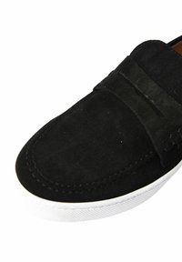 Scarpa nera in camoscio senza lacci con punta arrotondata, dotata di una fascia testurizzata e suola in gomma bianca. I dettagli delle cuciture esaltano il design minimalista.