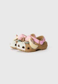 Colorful clogs featuring a half-white, half-brown design, pink straps, and synthetic hair accents resembling a cartoon horse.
