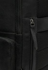 Zwarte leren rugzak met een gladde textuur, contrasterend zwart gaaspaneel en robuuste ritsen met metalen trekkoorden.